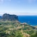 A coastal landscape with hills, scattered houses and a steep cliff overlooking the ocean